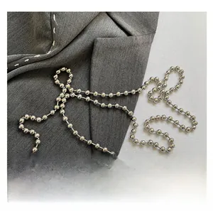 Detail of silver beaded chain strap and pearl clasp on blue denim shell crossbody bag