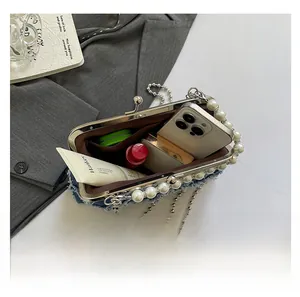 Internal capacity of denim shell bag with pearl trim showing phone and lipstick