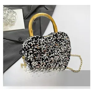 Close-up of heart-shaped evening bag with silver sequins and gold metal handle on blazer