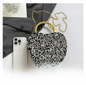 Detail of sequin evening bag with gold ring handle and chain on a gray blazer