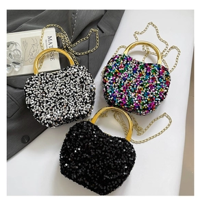 Detail view of heart-shaped glitter evening bags with metal ring handles and chain straps