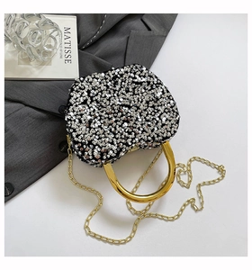 Detail of silver sequin handbag with gold metal handle and chain strap on a stylish background