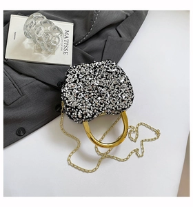 Close-up of sparkling silver sequin clutch bag with metallic gold ring handle and chain