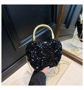Close-up of heart-shaped black sequin handbag with gold metal ring handle and chain