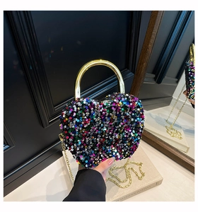 Detail of a heart-shaped evening clutch with multi-colored sequins and a gold metal handle