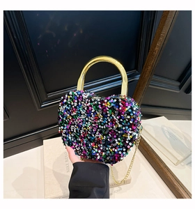 Detail of heart-shaped glitter evening bag with gold circular handle and chain strap