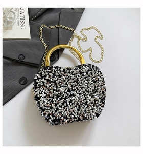 Detail of silver sequin evening bag with golden circular metal handle and chain strap