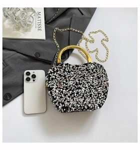 Detailed top view of black sequin handbag with gold metal handles and chain strap