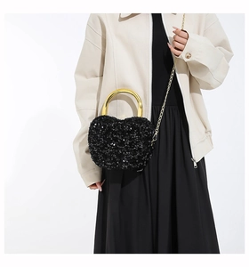 Close-up of black sequin heart handbag with gold U-shaped metal handle and chain
