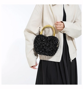 Detail of heart-shaped black sequin bag with gold U-shaped handle and chain strap