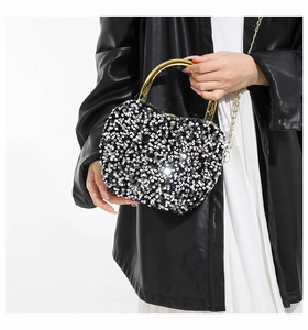 Detail of heart-shaped sequin handbag with gold circular handle and metal chain strap