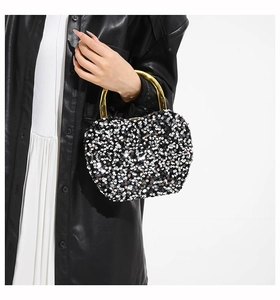 Fashionable black and white sequin box bag with gold round handle on model in leather jacket