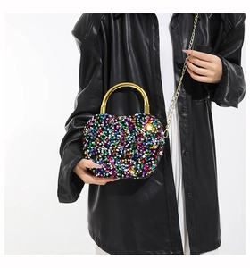Detail view of heart-shaped evening clutch featuring colorful sequins and metal handle
