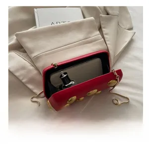 Sac boîte en cuir rouge montrant l'espace interne pour portable et parfum avec chaîne dorée