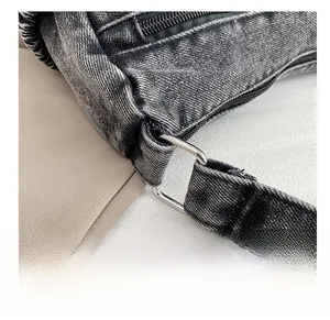 Détail de la boucle en métal argenté et de la texture denim gris délavé du sac bandoulière