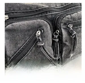 Détail des fermetures éclair argentées sur un sac à bandoulière en denim gris foncé
