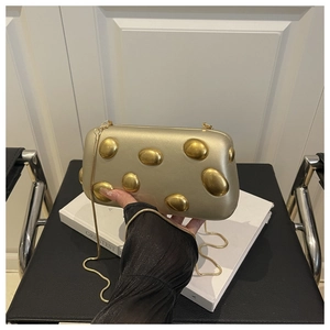 Détail de la pochette de soirée dorée avec ornements 3D en galets et bandoulière chaîne