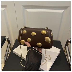 Détail du sac boîte en cuir marron foncé avec ornements dorés et bandoulière chaîne