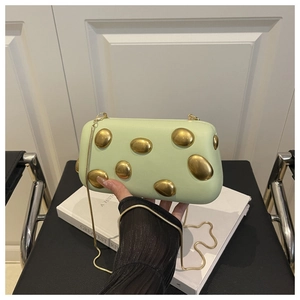 Détail de pochette en cuir vert clair avec ornements dorés et fine chaîne serpent
