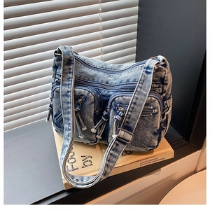 Gros plan détaillé du sac bandoulière en jean bleu délavé avec plusieurs poches zippées