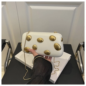 Détail de pochette de soirée blanche avec ornements dorés et bandoulière en chaîne