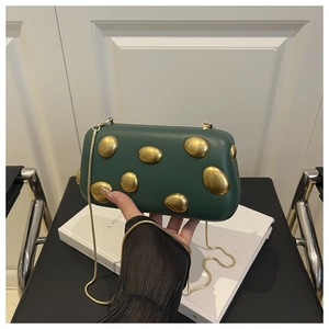 Détail du sac pochette vert foncé en acrylique avec chaîne dorée et ornements 3D dorés