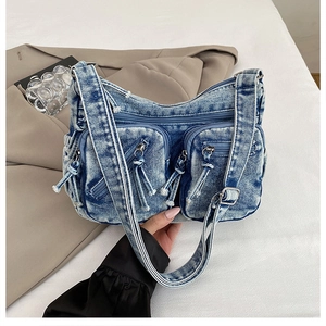 Détail du sac messager en denim délavé bleu avec poches zippées et bandoulière réglable