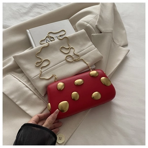 Détail de la pochette rouge mate avec ornements dorés et fine bandoulière en chaîne
