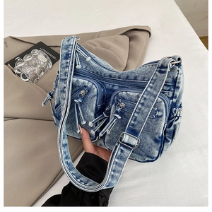Détail du sac bandoulière en denim délavé avec poches zippées et bandoulière réglable