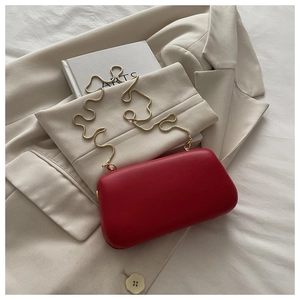 Gros plan d'une pochette rouge élégante avec chaîne dorée de luxe et fermoir métal