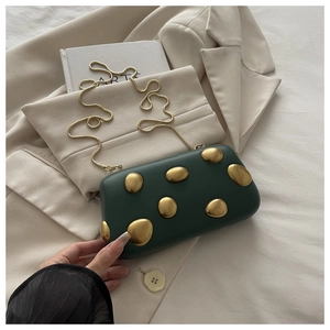 Détail du sac boîte vert foncé avec clous dorés et élégante bandoulière chaîne serpent