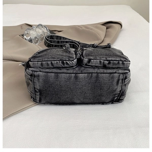Détail du sac bandoulière en denim noir délavé avec deux poches zippées sur le devant