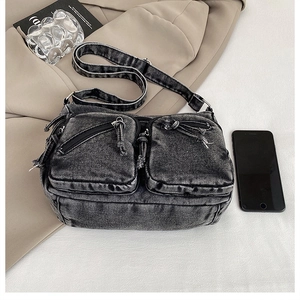 Vue détaillée du sac bandoulière en denim noir délavé avec deux poches zippées avant