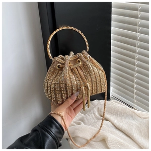 Macro detail of golden rhinestone bucket bag with drawstring tassels and metal ring handle