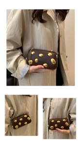 Détail du sac boîte marron foncé avec ornements de galets dorés et bandoulière chaîne