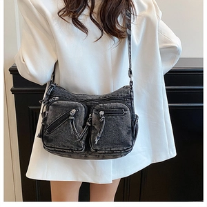 Gros plan du sac bandoulière en denim lavé avec plusieurs poches et fermetures éclair