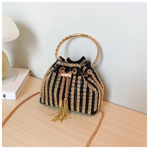 Detail of black bucket bag with golden rhinestones, metal tassels and chain strap