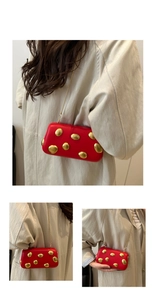 Détails de la pochette en cuir rouge avec boucles dorées et bandoulière en chaîne