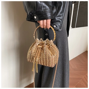 Detailed view of a gold rhinestone bucket bag with tassel drawstring and metal handle