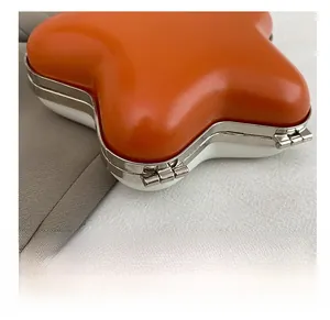 Detail showing the premium silver metal hinge of this orange star-shaped mini handbag