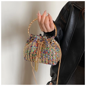 Detail of colorful rhinestone bucket bag with gold handle held by a model