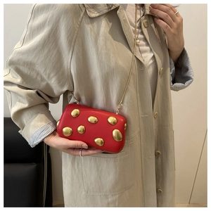 Petit sac bandoulière rouge avec boutons dorés porté avec un trench-coat beige élégant