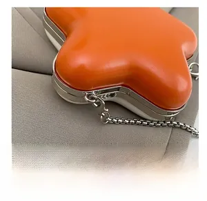 Detail of premium silver lobster clasp and metal chain on star-shaped orange mini bag