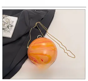Macro detail of sphere evening bag with orange marble texture and gold chain strap