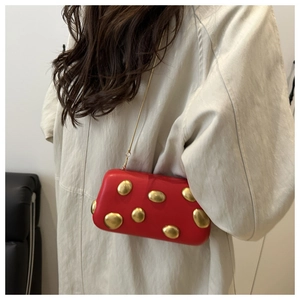 Vue détaillée du sac boîte rouge avec rivets dorés métalliques et bandoulière chaîne
