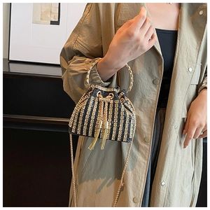 Detail of evening bucket bag with rhinestone stripes, gold tassels and ring handle