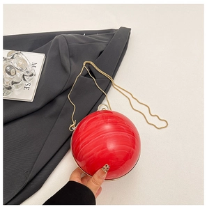 Macro detail of red marble acrylic spherical clutch bag with golden chain strap