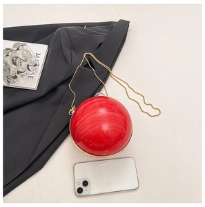 Detail of red marble-textured acrylic ball bag with gold chain and phone for scale