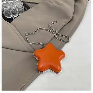 Detail of star-shaped orange mini lipstick bag with silver metal ball chain and glossy finish
