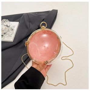 Detail of pink satin lining inside transparent acrylic sphere evening bag with gold chain